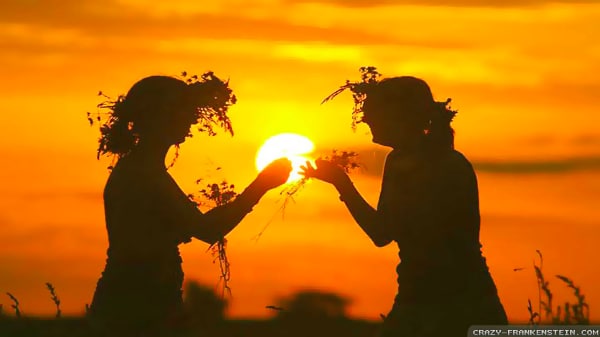 Share the gift that is you, two people sharing flowers in front of a orange sunset.