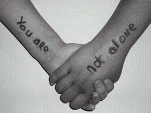 children holding hands, left arm has "You Are", right arm has "Not Alone" written on them.